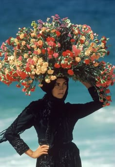 a woman with flowers on her head walking along the beach