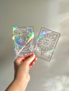 the moon tarot card is being held up by someone's hand with holographics on it