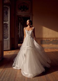 a woman in a wedding dress standing on a wooden floor with her back turned to the camera