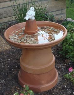 a birdbath with rocks in it and a small white statue sitting on top