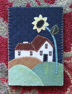 a small patch with a house and a sunflower on it sitting on a blanket