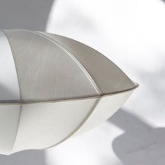 a close up view of a metal object on a white surface with shadows from it