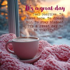 a cup of coffee sitting on top of a pink blanket with the words it's a great day to feel positive