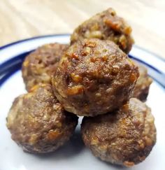 several meatballs stacked on top of each other on a blue and white plate with a wooden table in the background