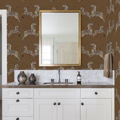 a bathroom with a mirror, sink and wallpaper in brown color that has zebras on it