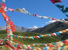 there are many colorful flags hanging in the air on this mountain side area with mountains in the background