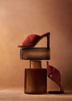 a pair of red shoes sitting on top of a stack of books in front of a brown wall