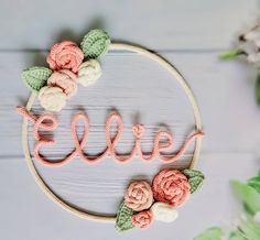 the word love spelled with crochet flowers on a wooden hoop next to greenery