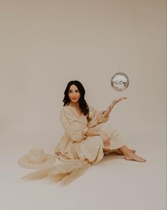 a woman is sitting on the floor with her hat and dress in front of her