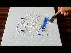 someone is using a brush to paint the outline on a canvas with blue and white ink