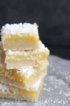 three pieces of lemon bars stacked on top of each other with powdered sugar all over them