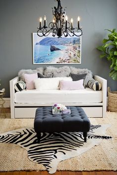 a living room with a couch, coffee table and chandelier hanging from the ceiling