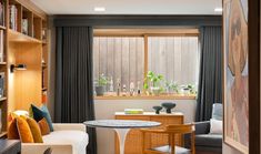 a living room filled with furniture and bookshelves next to a window covered in curtains