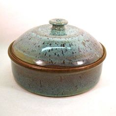 a brown and green ceramic covered dish on a white surface