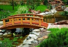 a wooden bridge over a small pond in a garden