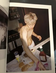 an old photo of a shirtless boy in the kitchen