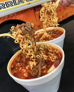 two white cups filled with noodles and meat