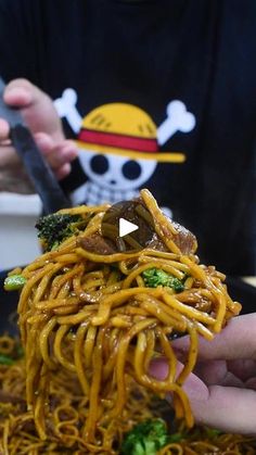 someone is eating noodles and broccoli with chopsticks