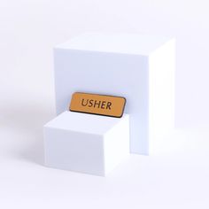 a white cube with a yellow sign that says usher on the front and bottom