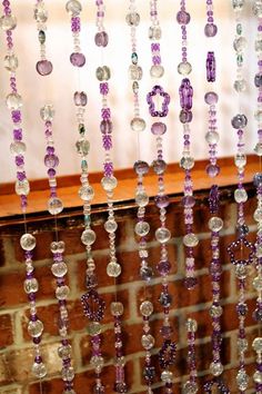 beads hanging from the side of a window in front of a brick wall and wooden ledge