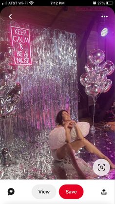 a woman sitting on the floor in front of balloons and streamers with her eyes closed