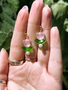 a person is holding two rings with flowers on them and green leaves in the background