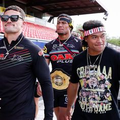 three men standing next to each other in front of a crowd at a sporting event