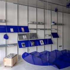 an empty room with blue shelves and pictures on the wall, suspended from metal bars