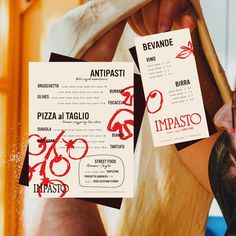 two pizza menus are being held up to the camera man's face in front of them