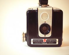 an old brownie hawkeye camera sitting on a white surface with the lens up