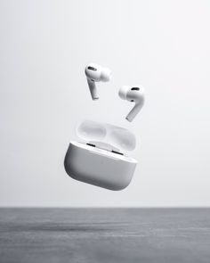 an airpods is flying through the air with its cover open and ear buds out