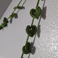 green crocheted flowers are attached to a white wall with water droplets on it