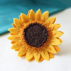 a yellow and brown sunflower sitting on top of a white table next to a blue cloth