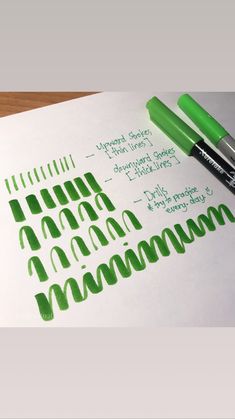 some green markers are sitting on top of a piece of paper