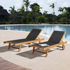 two lounge chairs sitting next to a swimming pool