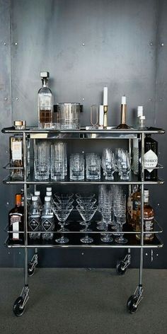 a metal bar cart filled with glasses and liquor bottles on top of eachother