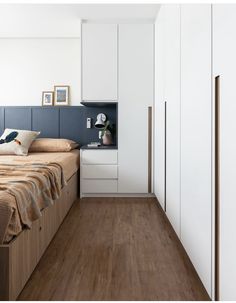 a bed room with a neatly made bed and white cupboards on the wall next to it