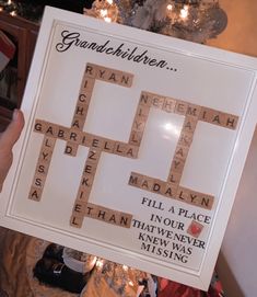 a person holding up a scrabble board in front of a christmas tree