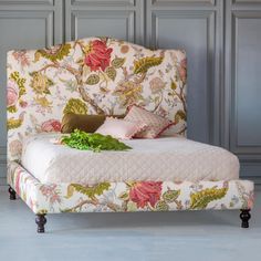 a bed with floral upholstered headboard and foot board, sitting against a wall