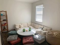 a living room filled with furniture and a white table surrounded by pillows on the floor