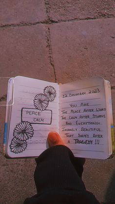 a person holding an open book with writing on it in front of a brick sidewalk