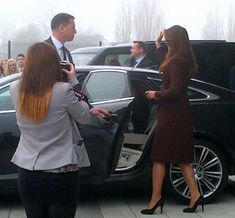 two women are getting out of a car and talking to a man in a suit