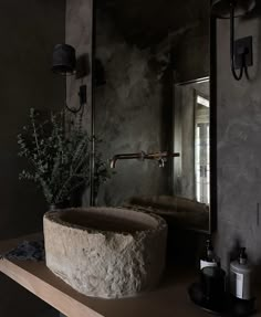 a stone sink sitting on top of a wooden counter next to a wall mounted mirror