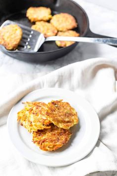 some food is sitting on a white plate next to a skillet and spatula