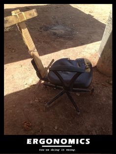 an old chair sitting on the ground next to a wooden pole with a sign that says ergonomics