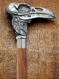 a metal bird head on top of a wooden table next to a wood handled hammer