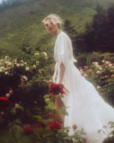 a woman in a white dress walking through flowers