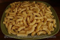 a green plate filled with pasta on top of a wooden table