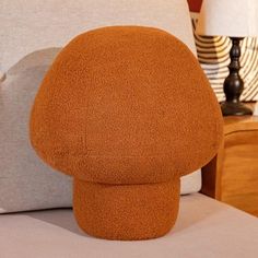 a close up of a pillow on a bed with a lamp in the back ground