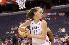 a women's basketball player dribbling the ball in front of an audience